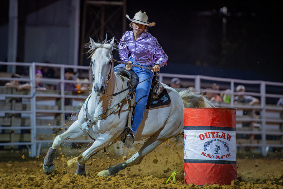 Richeson on a grey horse cutting hard around the Outlaw barrel