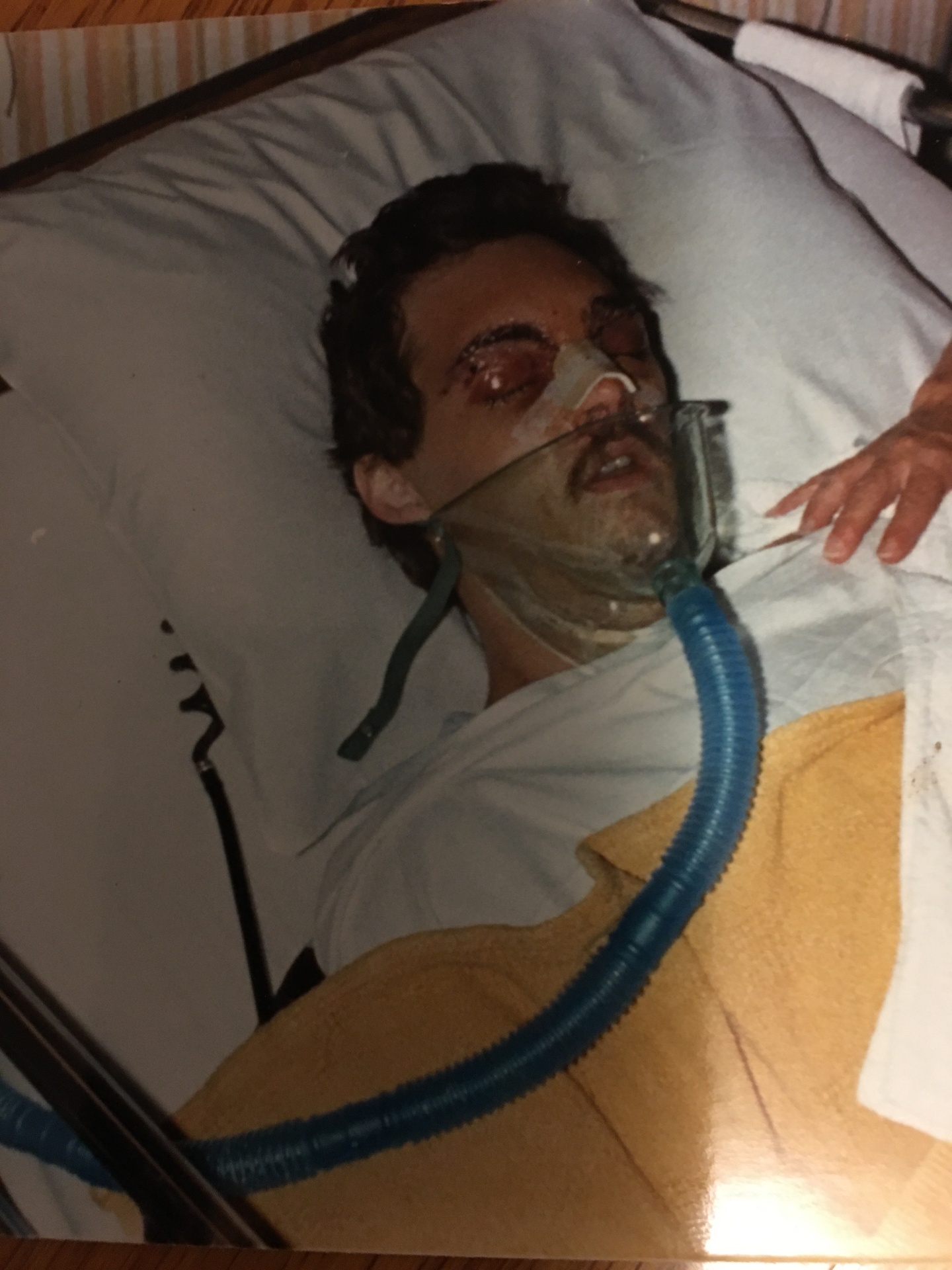 Travis Presley lying in a hospital bed, sedated and bandaged after the bull-riding wreck that shattered his face — a hand rests on his shoulder in support